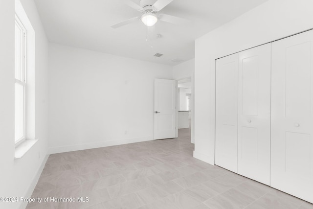 unfurnished bedroom with ceiling fan and a closet