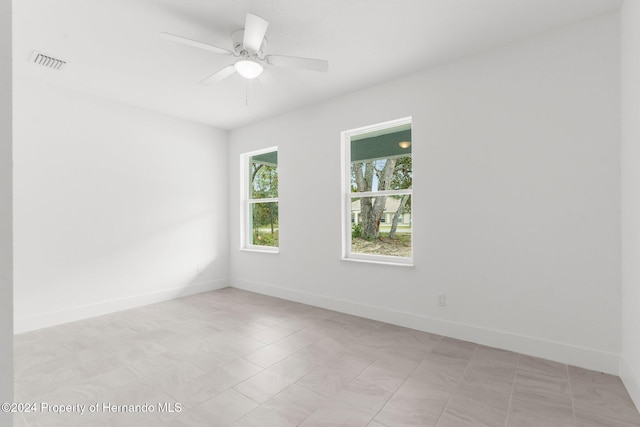 tiled spare room featuring ceiling fan