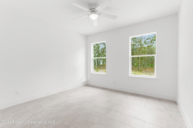 spare room featuring ceiling fan, a healthy amount of sunlight, and light tile patterned floors