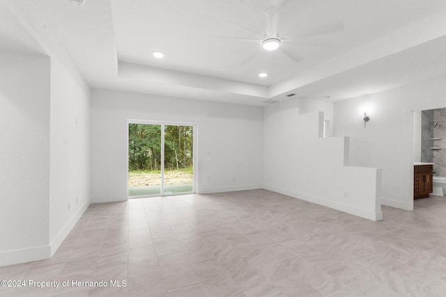 empty room featuring ceiling fan and a raised ceiling