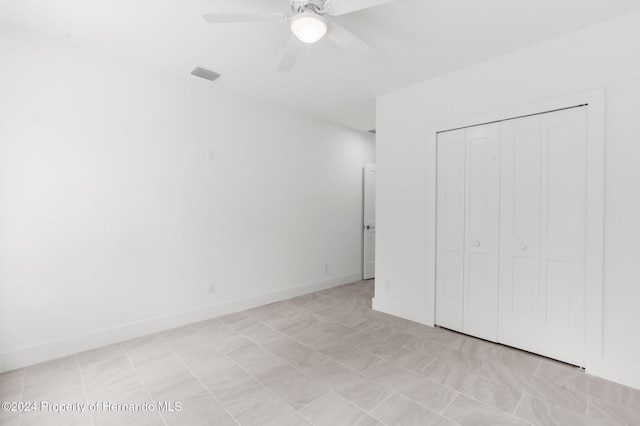 unfurnished bedroom with ceiling fan and a closet