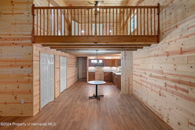 unfurnished living room with wood walls, wood-type flooring, and ceiling fan