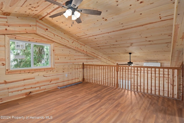 additional living space featuring lofted ceiling, wood walls, hardwood / wood-style flooring, wooden ceiling, and ceiling fan