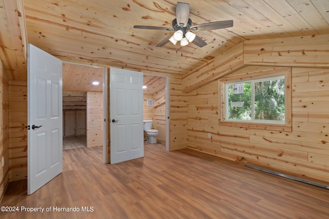 additional living space with lofted ceiling, wood ceiling, wooden walls, hardwood / wood-style flooring, and ceiling fan