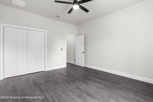 unfurnished bedroom featuring a textured ceiling, dark hardwood / wood-style flooring, a closet, and ceiling fan