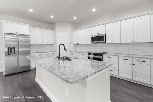 kitchen featuring sink, white cabinets, stainless steel appliances, and a center island with sink