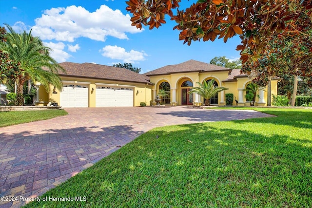 mediterranean / spanish house featuring a garage and a front lawn