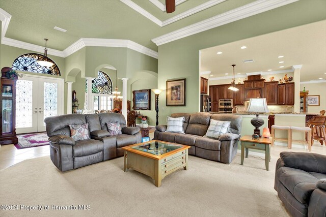 carpeted living room featuring a high ceiling, sink, ornamental molding, ornate columns, and french doors