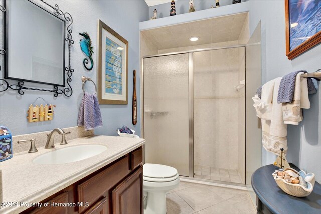 bathroom featuring toilet, vanity, an enclosed shower, and tile patterned flooring