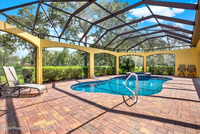 view of pool featuring glass enclosure, a patio, and an in ground hot tub