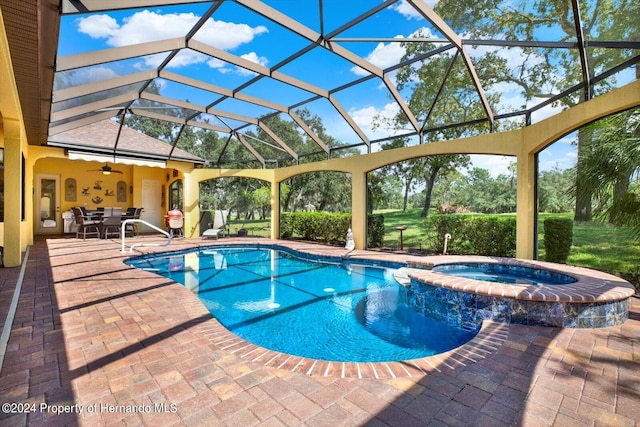 view of pool featuring an in ground hot tub, ceiling fan, glass enclosure, and a patio area