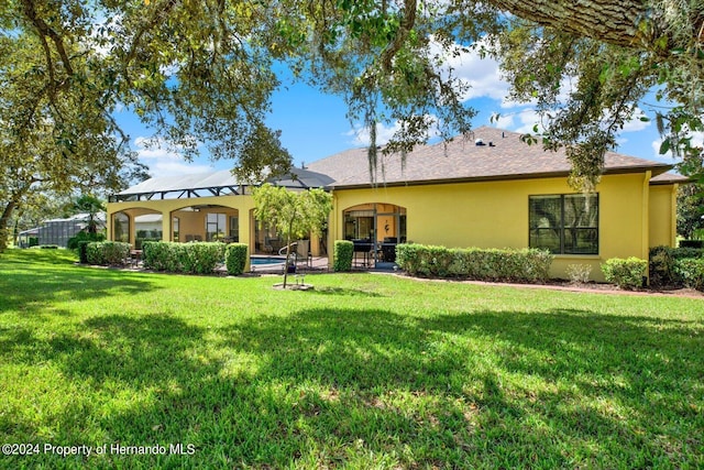 rear view of house with a lawn and a lanai