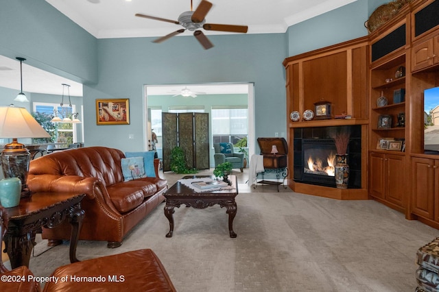 living room with ornamental molding, light carpet, ceiling fan, and a tile fireplace