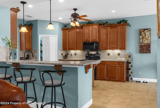 kitchen with black appliances, kitchen peninsula, decorative light fixtures, and light stone counters