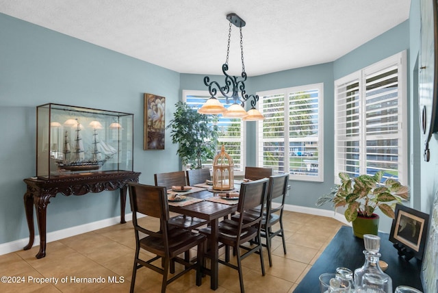 tiled dining space with a textured ceiling and a notable chandelier