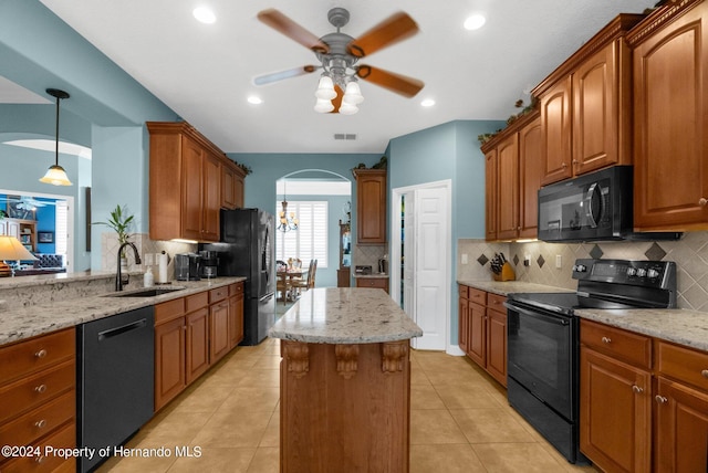 kitchen with light stone counters, black appliances, sink, tasteful backsplash, and a kitchen island