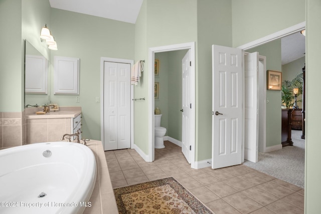 bathroom with tile patterned floors, vanity, high vaulted ceiling, toilet, and a relaxing tiled tub