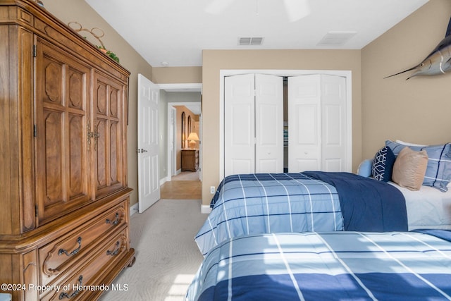 bedroom with ceiling fan, light carpet, and a closet