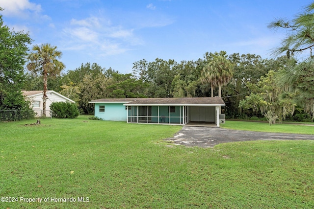 view of front of property featuring a sunroom, a carport, and a front lawn