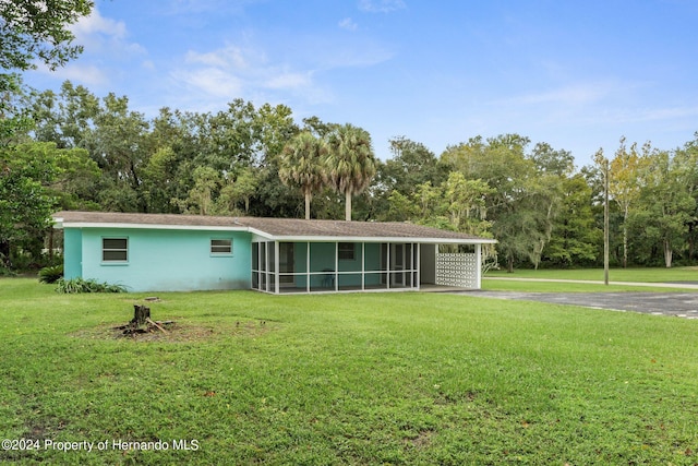 rear view of house with a lawn, a sunroom, and a carport