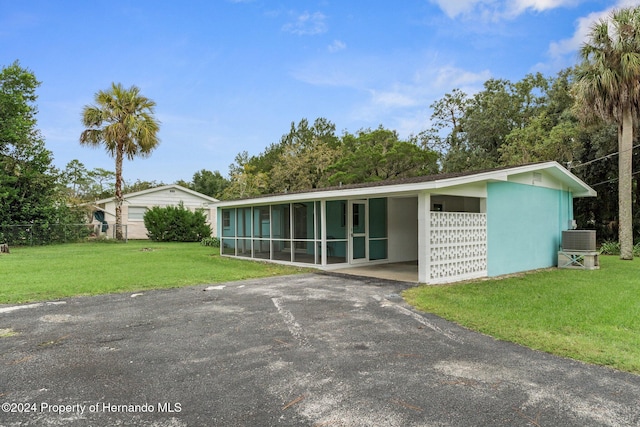 ranch-style house featuring central AC unit, a front yard, and a carport