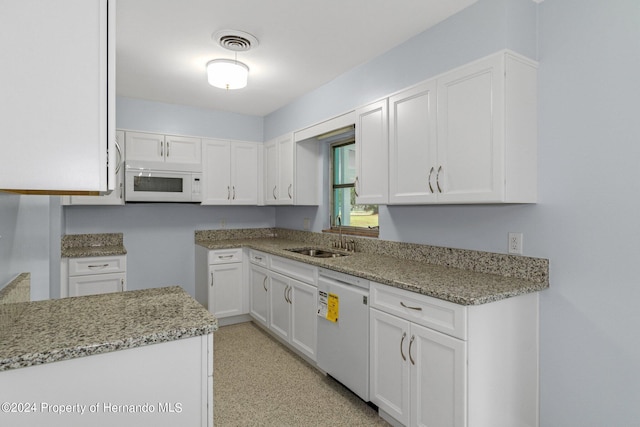 kitchen with white cabinetry, light stone counters, sink, and white appliances