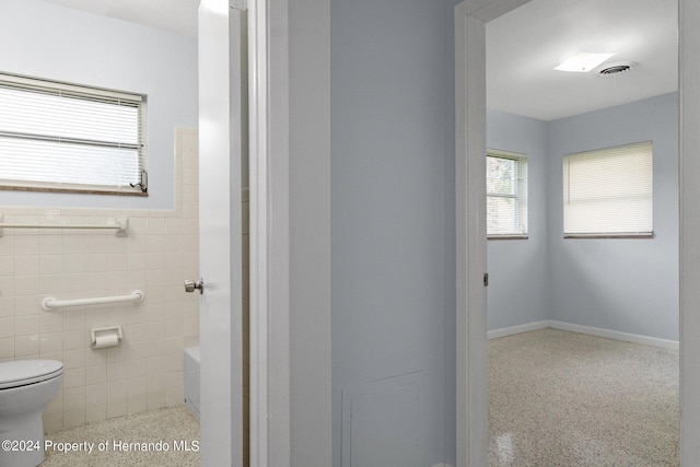 bathroom with toilet and tile walls