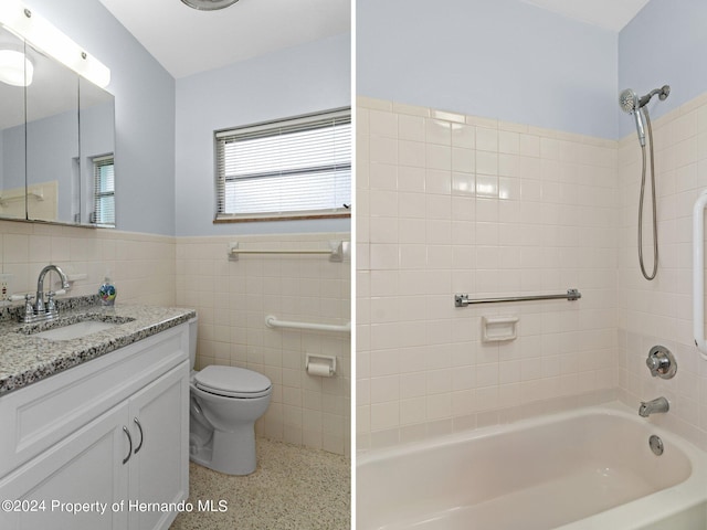 full bathroom featuring toilet, vanity, tiled shower / bath combo, and tile walls