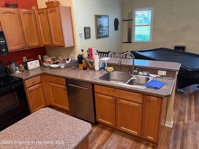 kitchen with hardwood / wood-style floors, sink, black appliances, and kitchen peninsula