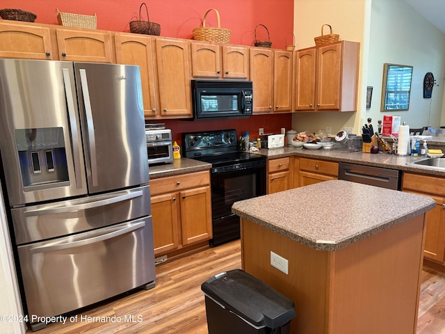 kitchen with light wood-type flooring, sink, black appliances, and a kitchen island