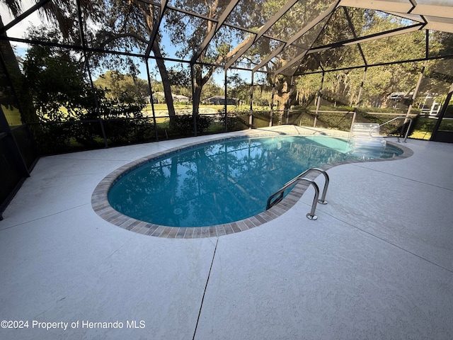 view of swimming pool with glass enclosure and a patio