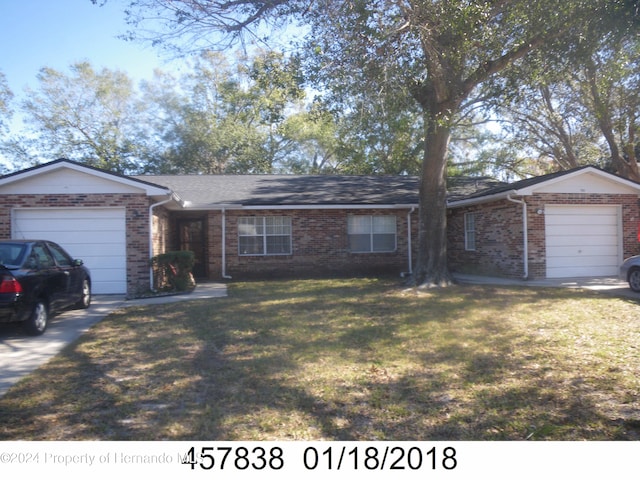 single story home featuring a front yard, brick siding, and an attached garage