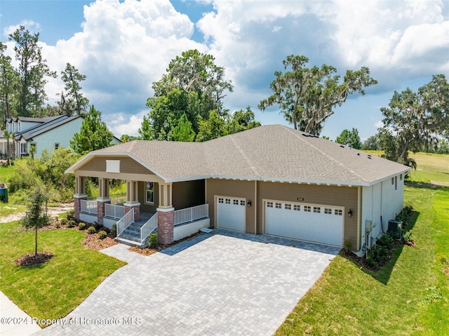 view of front of house featuring central air condition unit, a garage, a front yard, and a porch