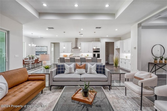 living room with wood-type flooring, an inviting chandelier, and a tray ceiling