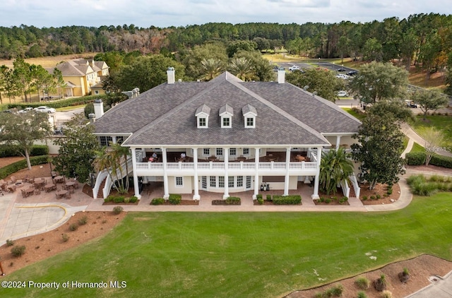 rear view of property featuring a balcony and a lawn