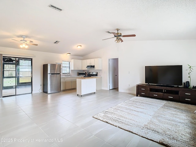 tiled living room featuring ceiling fan, sink, and lofted ceiling