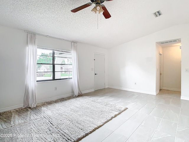 unfurnished room with ceiling fan and a textured ceiling