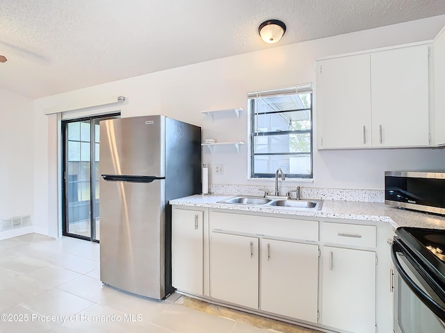 kitchen with white cabinets, a textured ceiling, stainless steel appliances, and sink