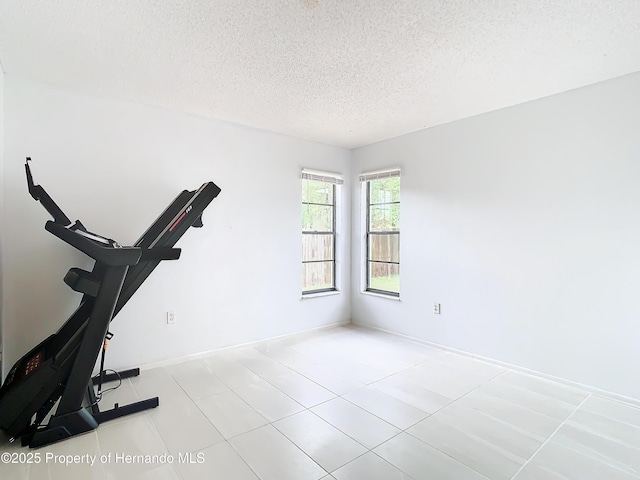 exercise area with light tile patterned flooring and a textured ceiling