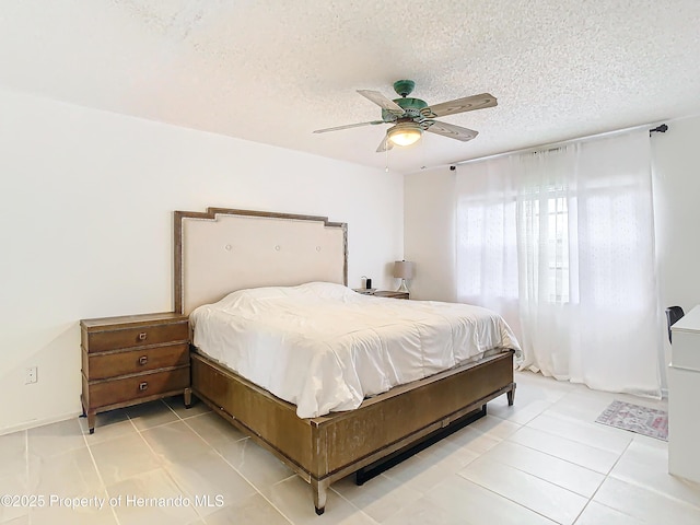 bedroom with ceiling fan, light tile patterned floors, and a textured ceiling