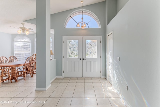 entryway featuring high vaulted ceiling, french doors, light tile patterned floors, and ceiling fan with notable chandelier