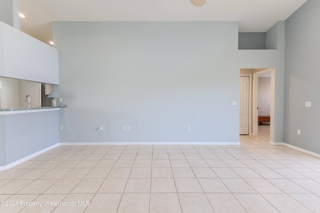 empty room with light tile patterned floors and a high ceiling