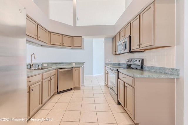 kitchen with sink, appliances with stainless steel finishes, light brown cabinets, light tile patterned floors, and decorative backsplash