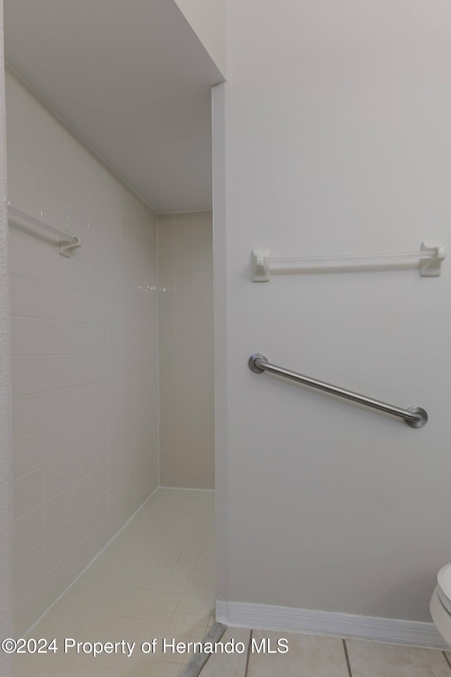 bathroom featuring toilet, tile patterned flooring, and a tile shower