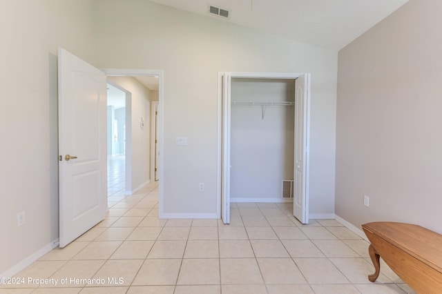 unfurnished bedroom with light tile patterned floors, a closet, and lofted ceiling