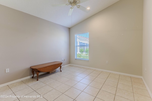 tiled empty room featuring lofted ceiling and ceiling fan