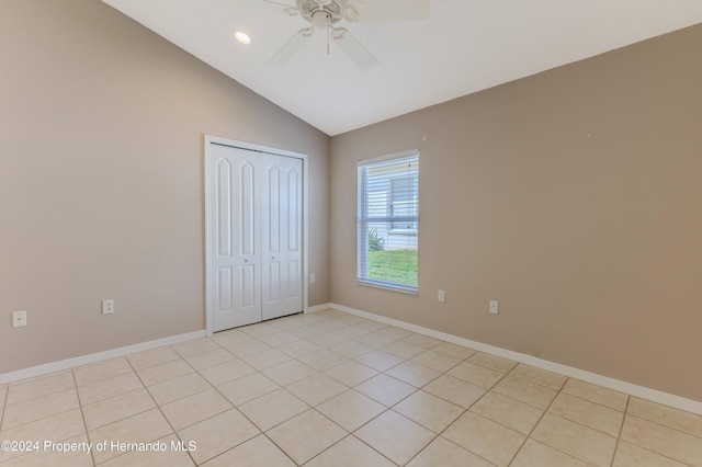 unfurnished bedroom featuring light tile patterned flooring, lofted ceiling, ceiling fan, and a closet