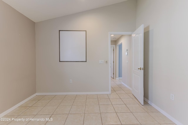 tiled spare room featuring lofted ceiling