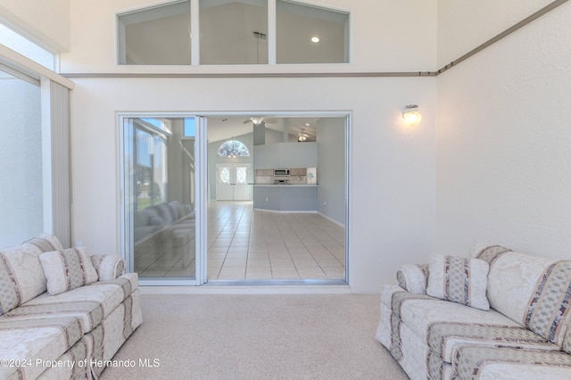 carpeted living room featuring high vaulted ceiling