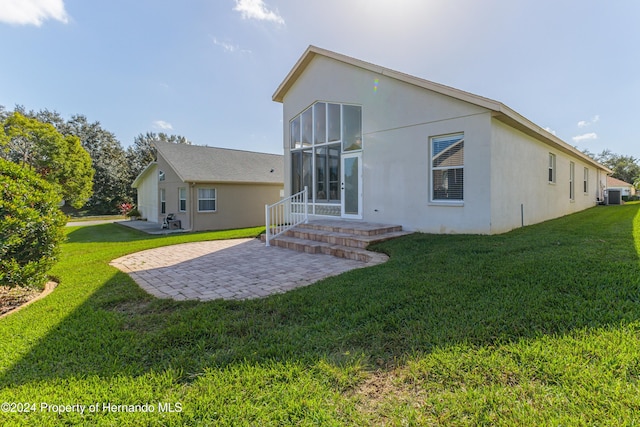 back of property featuring a patio area, a lawn, a sunroom, and cooling unit